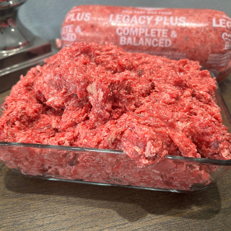 Legacy PLUS Complete & Balanced raw beef dog food log, red crumbles on glass tray