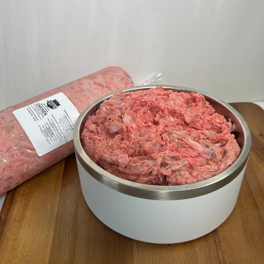 Raw chopped chicken in a stainless bowl with packaged meat beside it