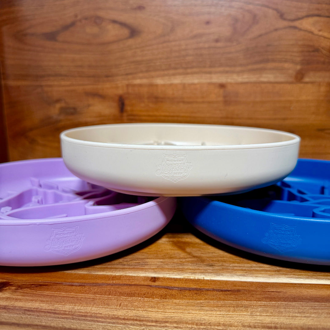 Stacked silicone pet bowls in white, purple, and blue with slow-feeder design