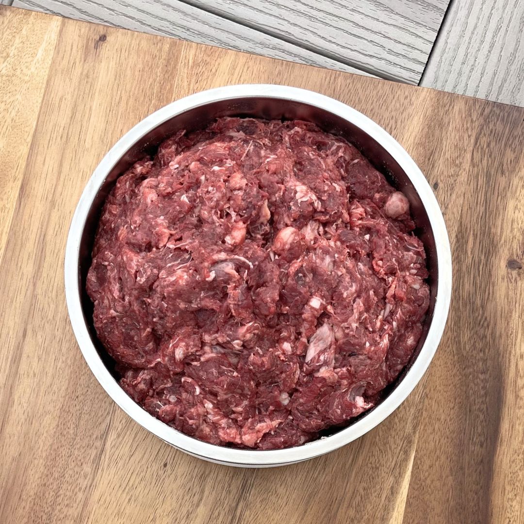beef liver tripe dog food in large circular dog food bowl on wooden cutting board